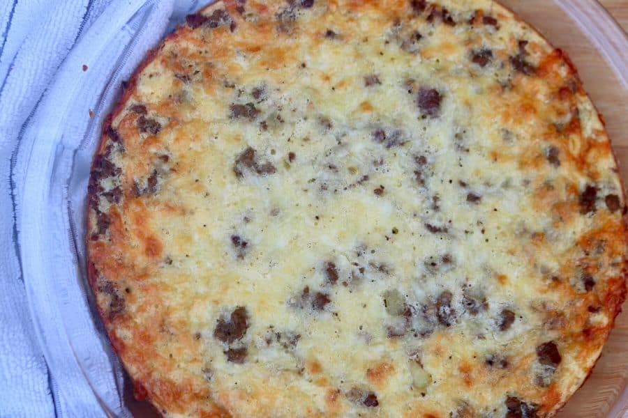 whole cheeseburger pie in a pie plate surrounded by a white and grey striped towel