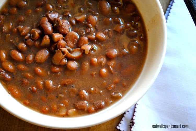 slow cooked pinto beans in a white bowl with a white napkin beside it