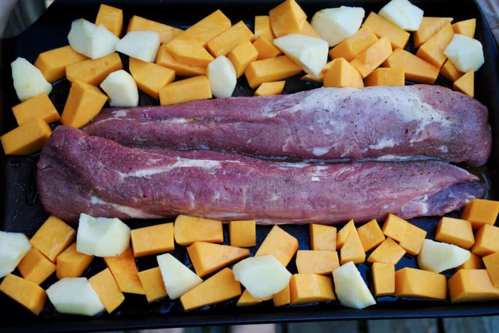 pork tenderloin, butternut squash, and apples on a baking sheet