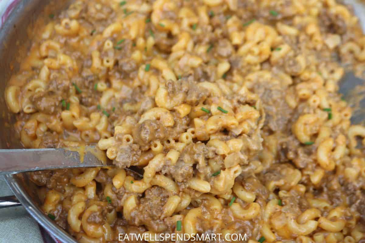 Spoon scooping cheeseburger macaroni from a skillet