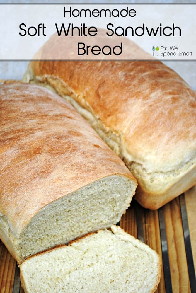 Two loaves of homemade white sandwich bread on a cutting board. One loaf is sliced.