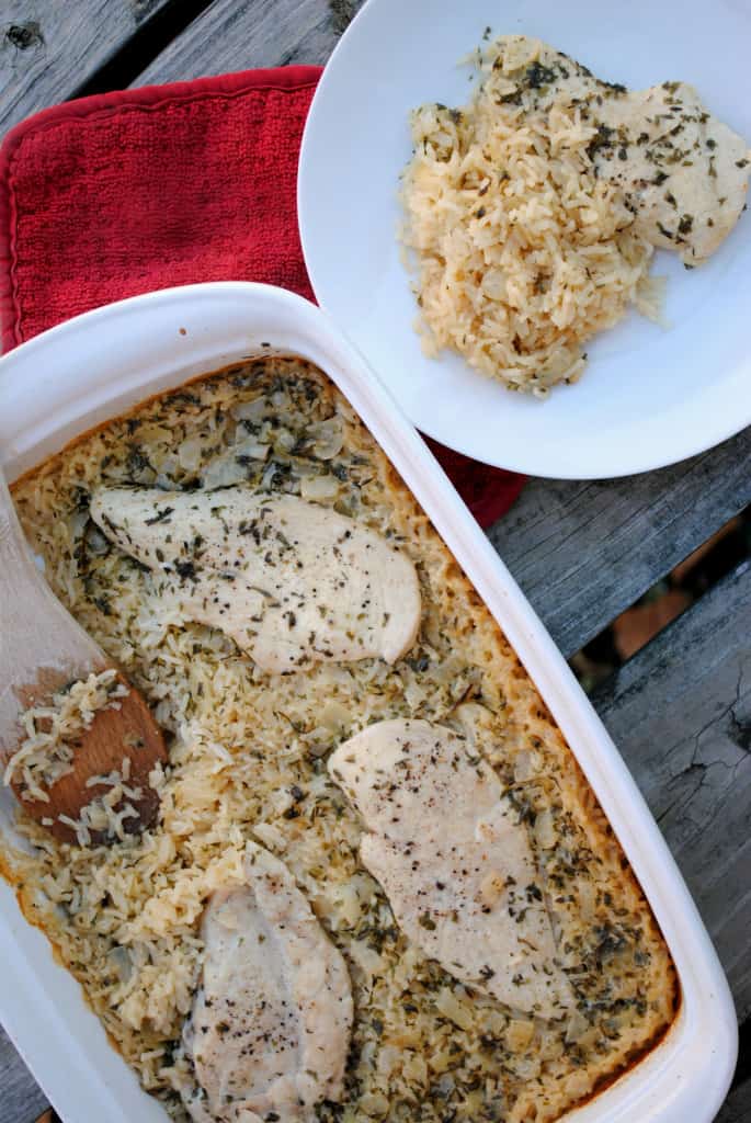 Wooden spoon scooping chicken on top of a bed of rice