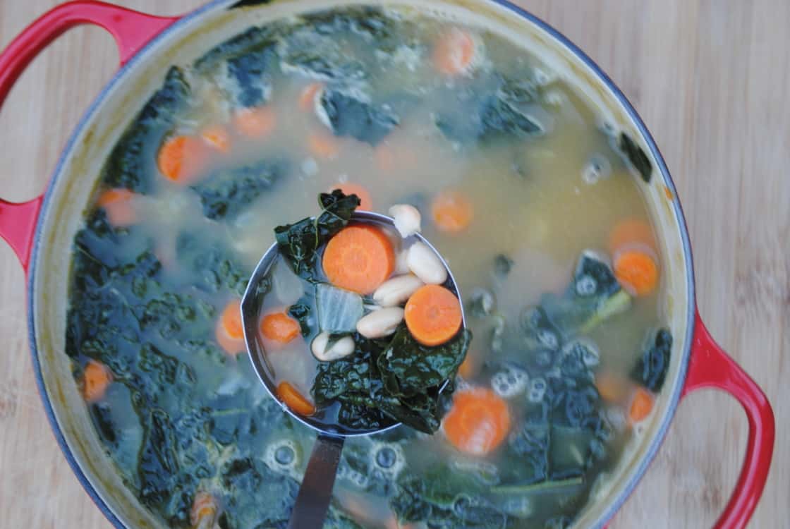 A ladle full of kale and white bean soup