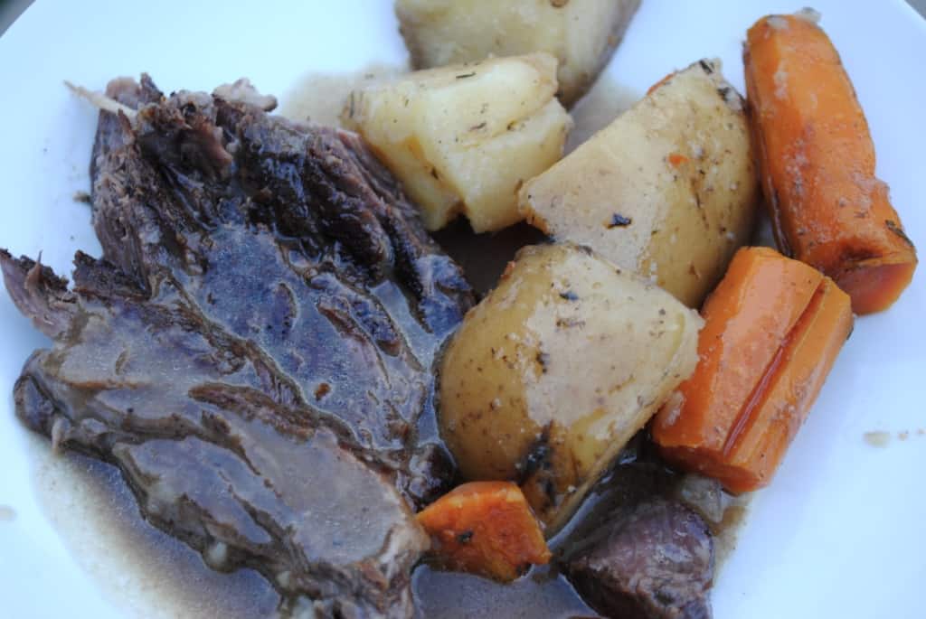 roast beef, potatoes, carrots, and gravy on a white plate