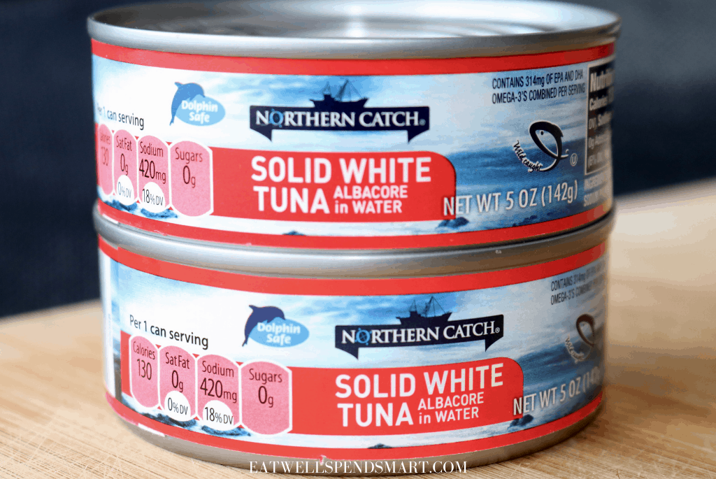 Two cans of tuna on a wooden board