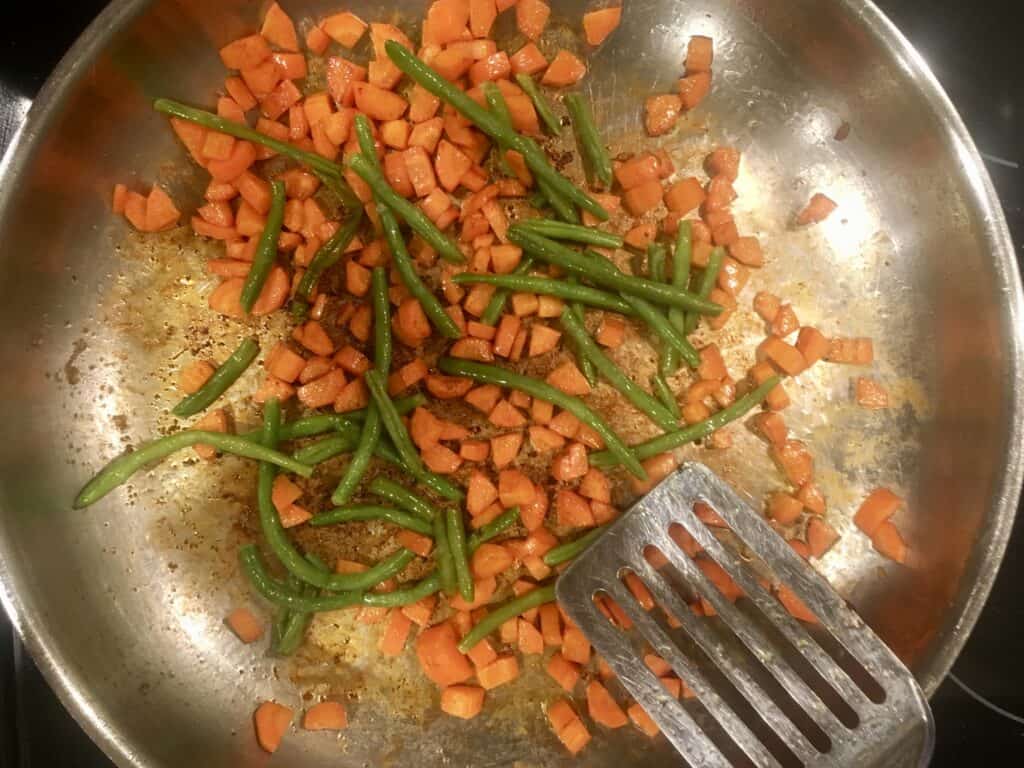 carrots and green beans cooking in a skillet