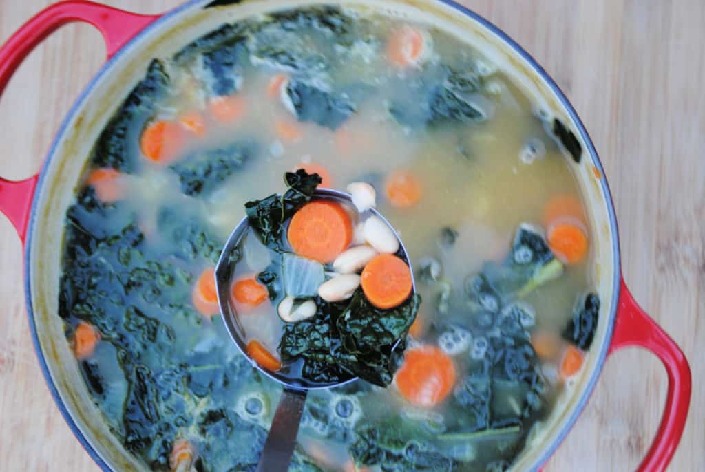 A ladle full of kale and white bean soup