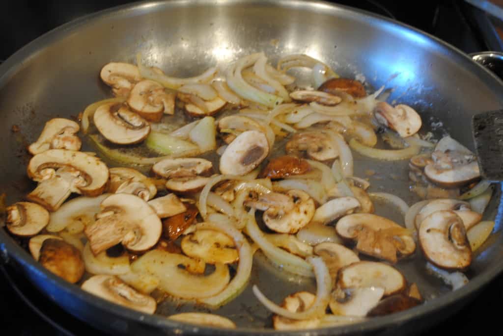 Onions and mushrooms sautéing in a skillet
