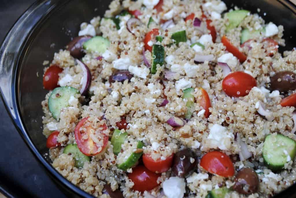 Greek quinoa salad with quinoa, tomatoes, cucumbers, olives, onions and feta in a bowl.
