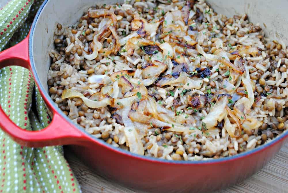 lentils and rice topped with caramelized onions in a red pot