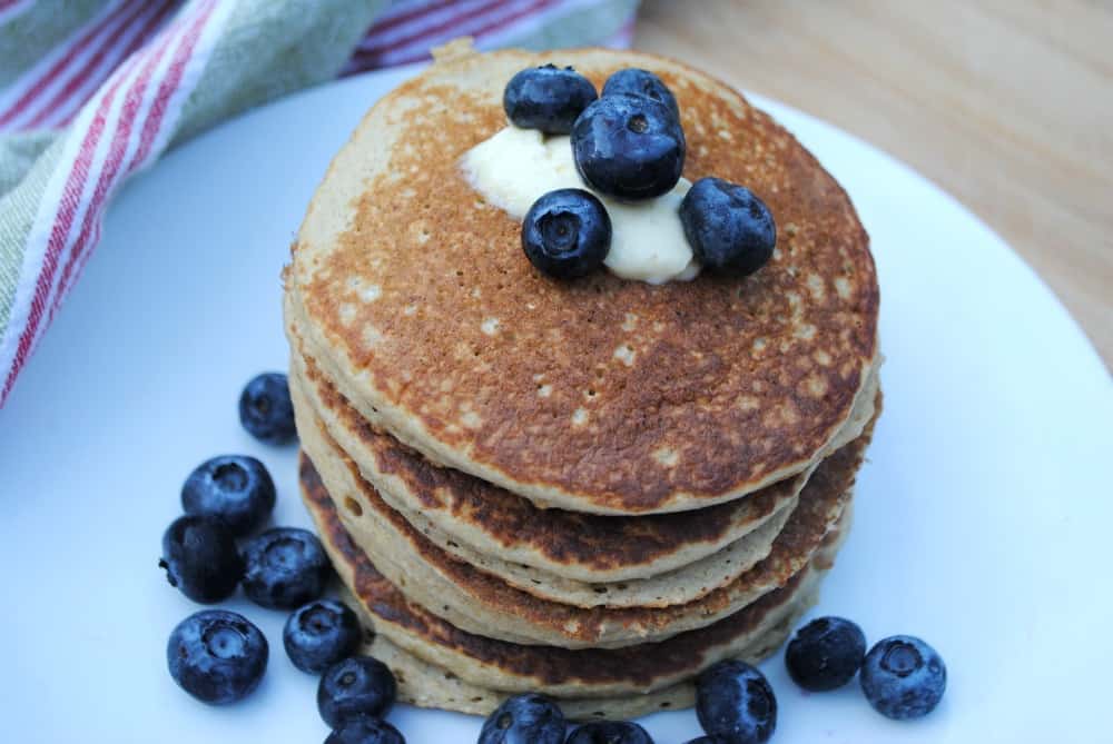 oat pancakes on a white plate and topped with blueberries