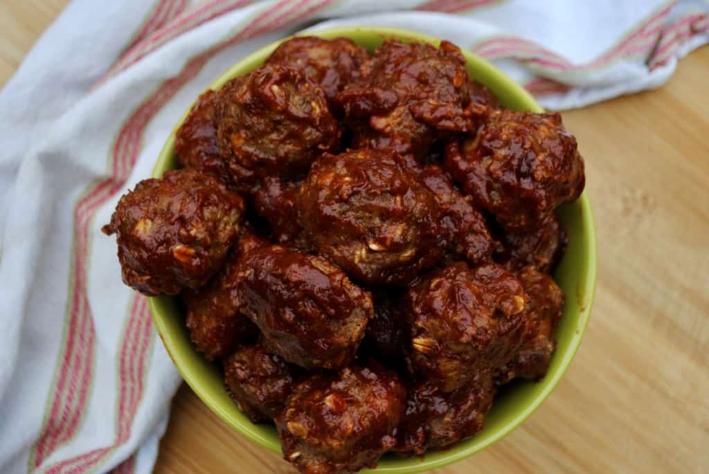 bbq meatballs in a green bowl with white striped towel in background