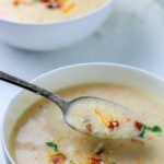 Spooning out potato soup from a white bowl