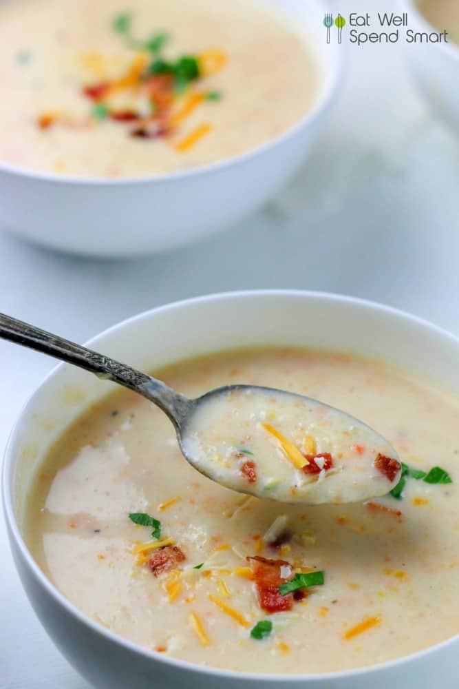 Spooning out potato soup from a white bowl