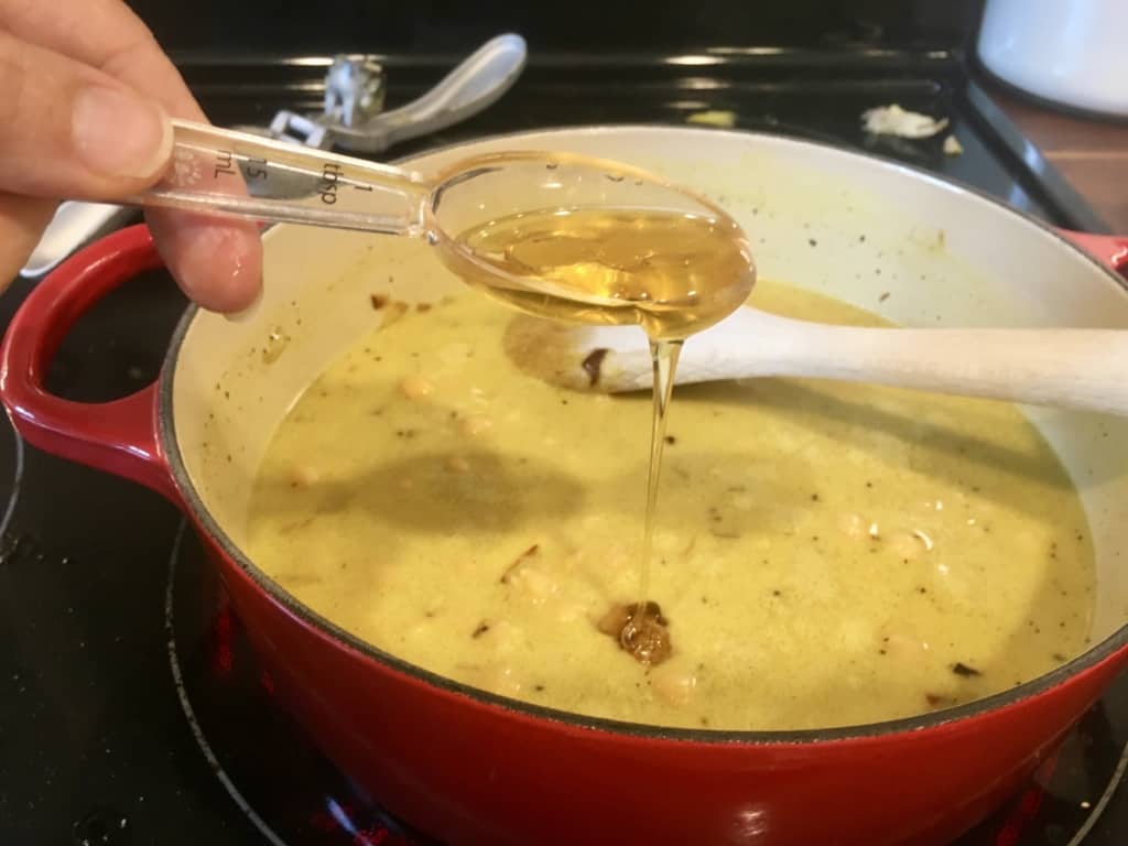 Honey being poured into chickpea curry sauce.