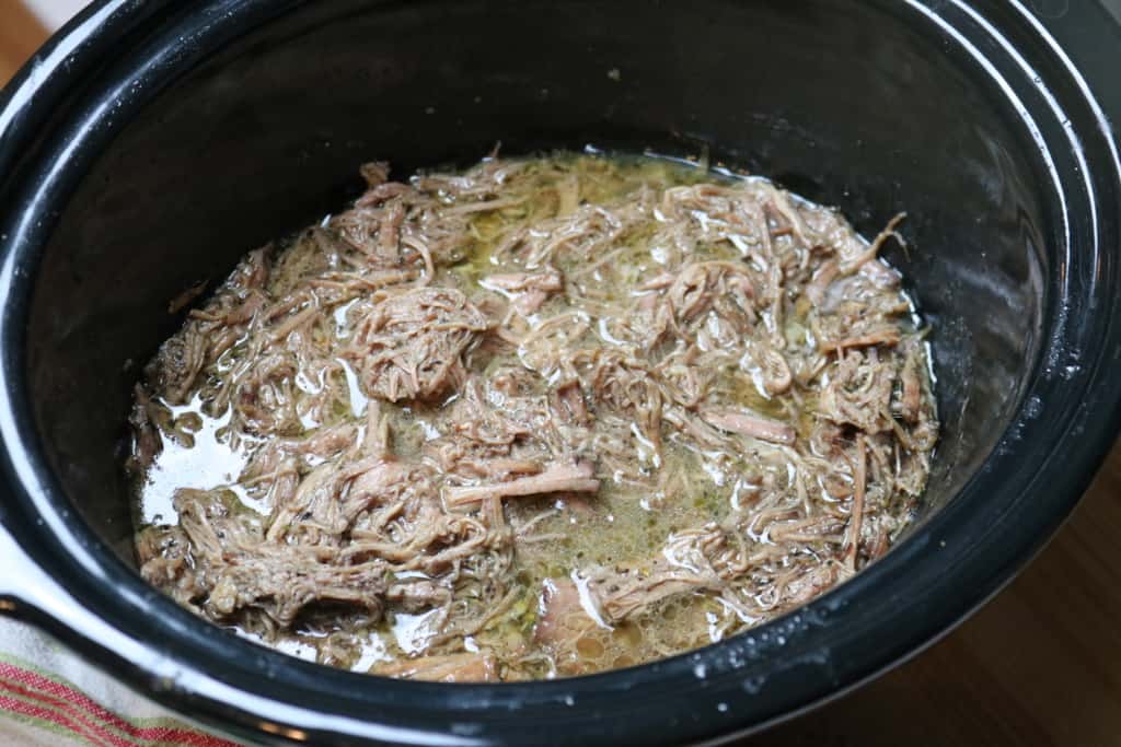 shredded Italian beef in a black slow cooker