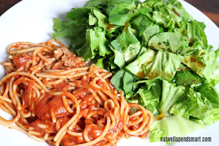 spaghetti and salad on a white plate