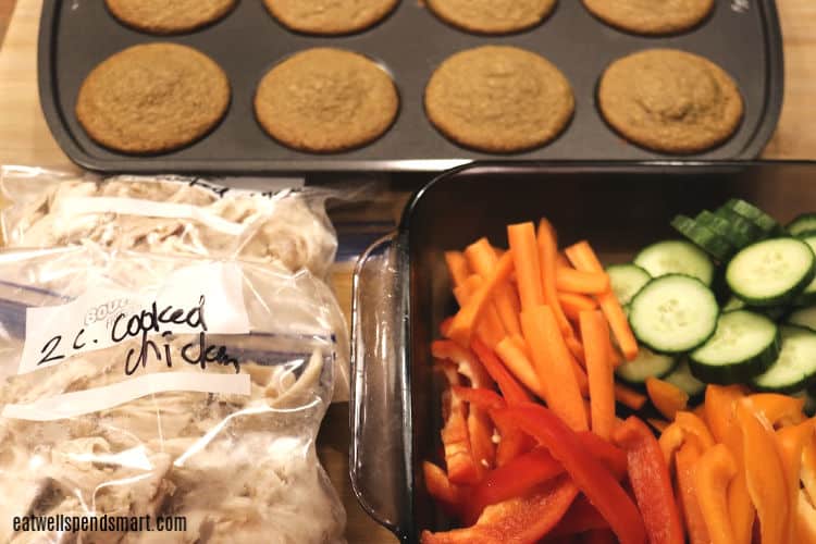 muffins, cut up veggies in a glass dish, and two bags of shredded chicken