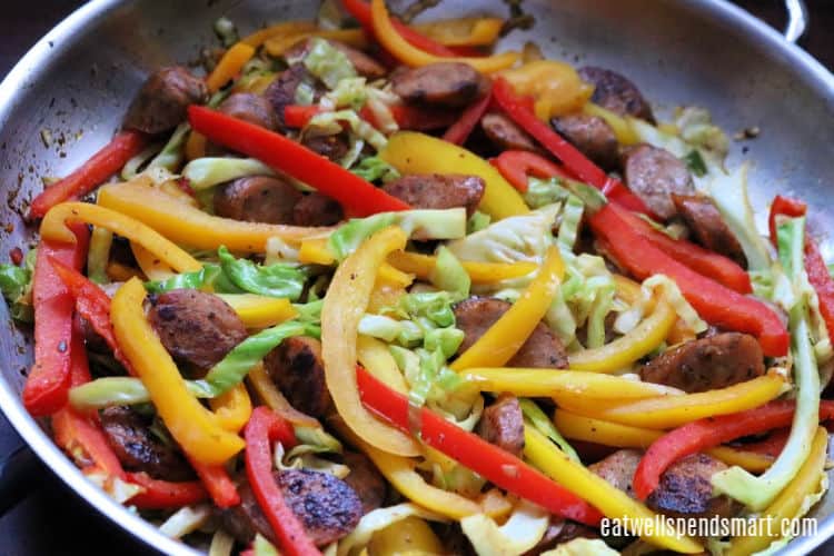 Stir fried sausage, peppers, and cabbage in a stainless steel skillet