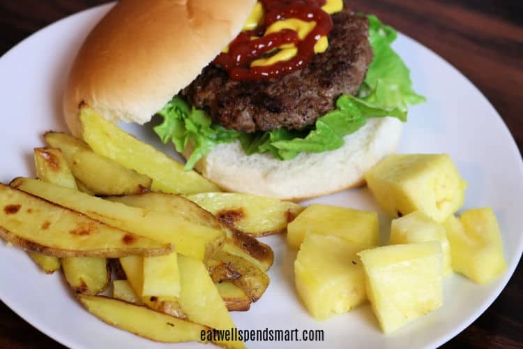 burger, oven fries, and cubed pineapple on a white plate