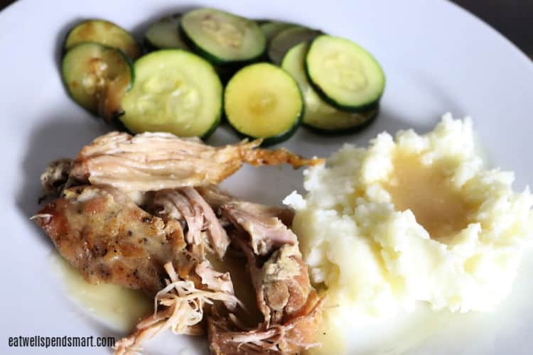 Pork roast, mashed potatoes and gravy, and sautéd zucchini on a white plate