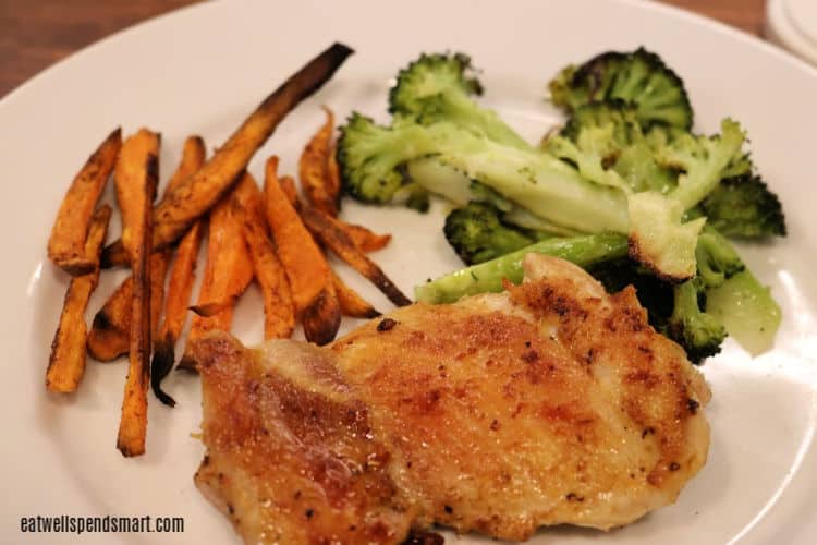 crispy chicken thigh, roasted broccoli, and sweet potato fries on a white plate
