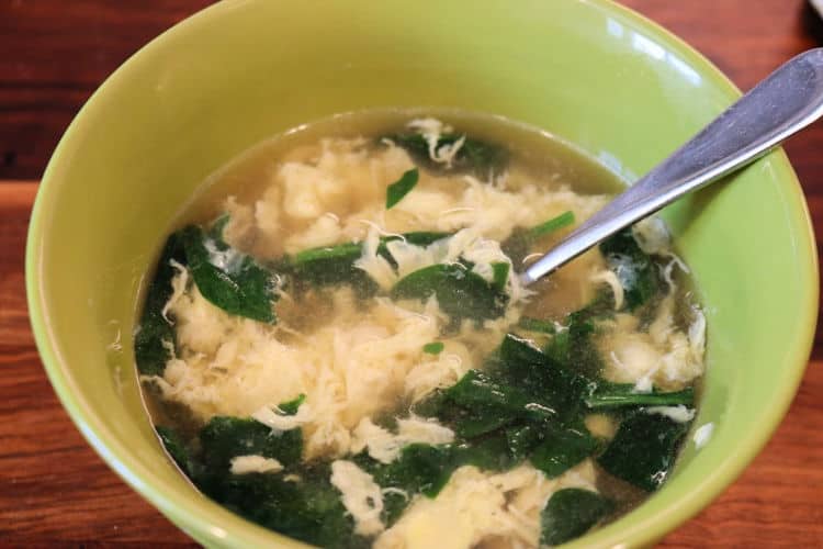 egg drop soup with spinach in a green bowl