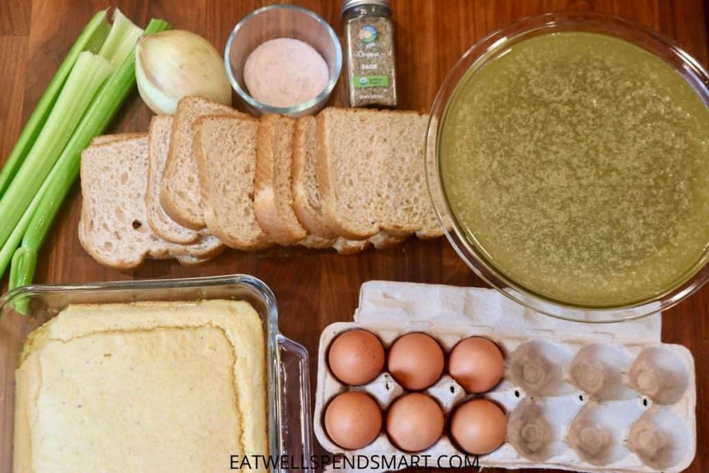celery, onion, salt, sage, broth, bread, cornbread, and eggs on a wooden board