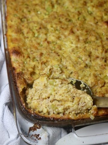 Spoon scooping cornbread dressing from a casserole dish