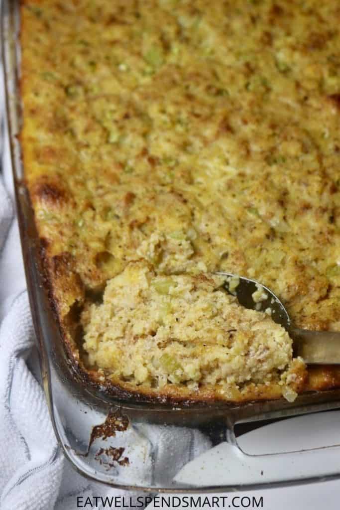 Spoon scooping cornbread dressing from a casserole dish