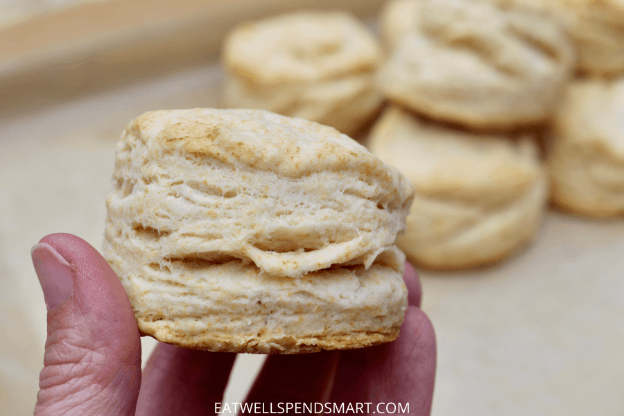 Hand holding a flaky homemade biscuit