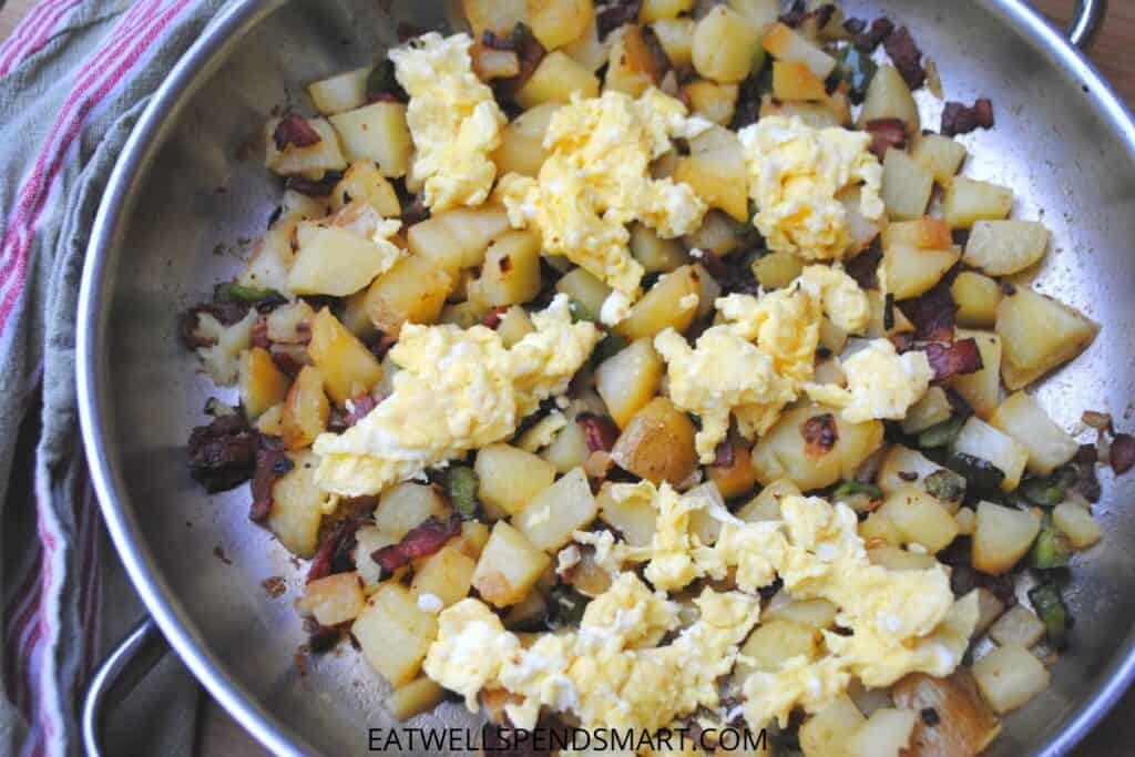 cubed potatoes, bacon, onion, peppers, and egg hash in a skillet