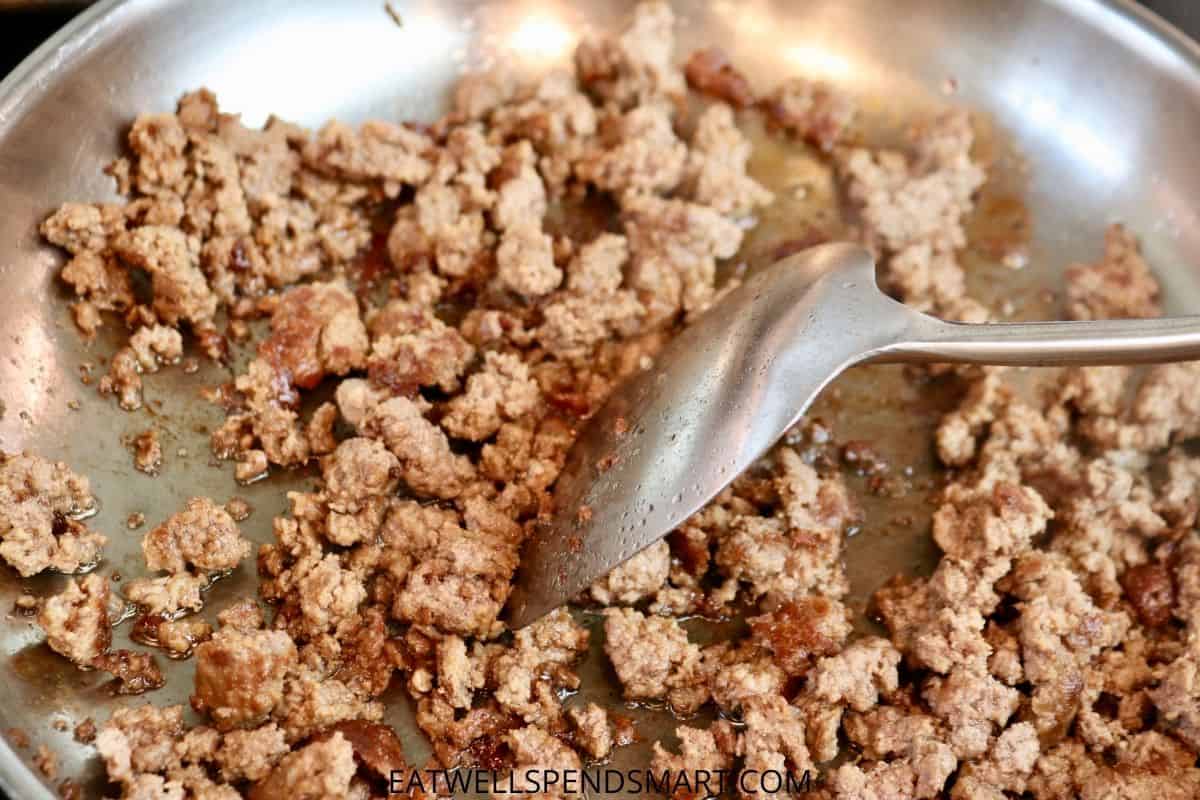 spatula breaking up cooked ground beef in a skillet