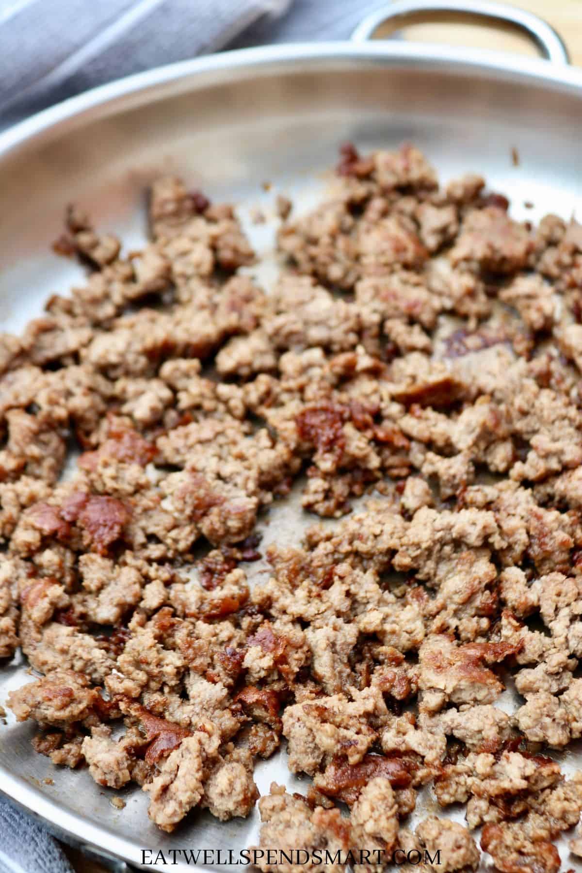 Browned ground beef in a large stainless steel skillet