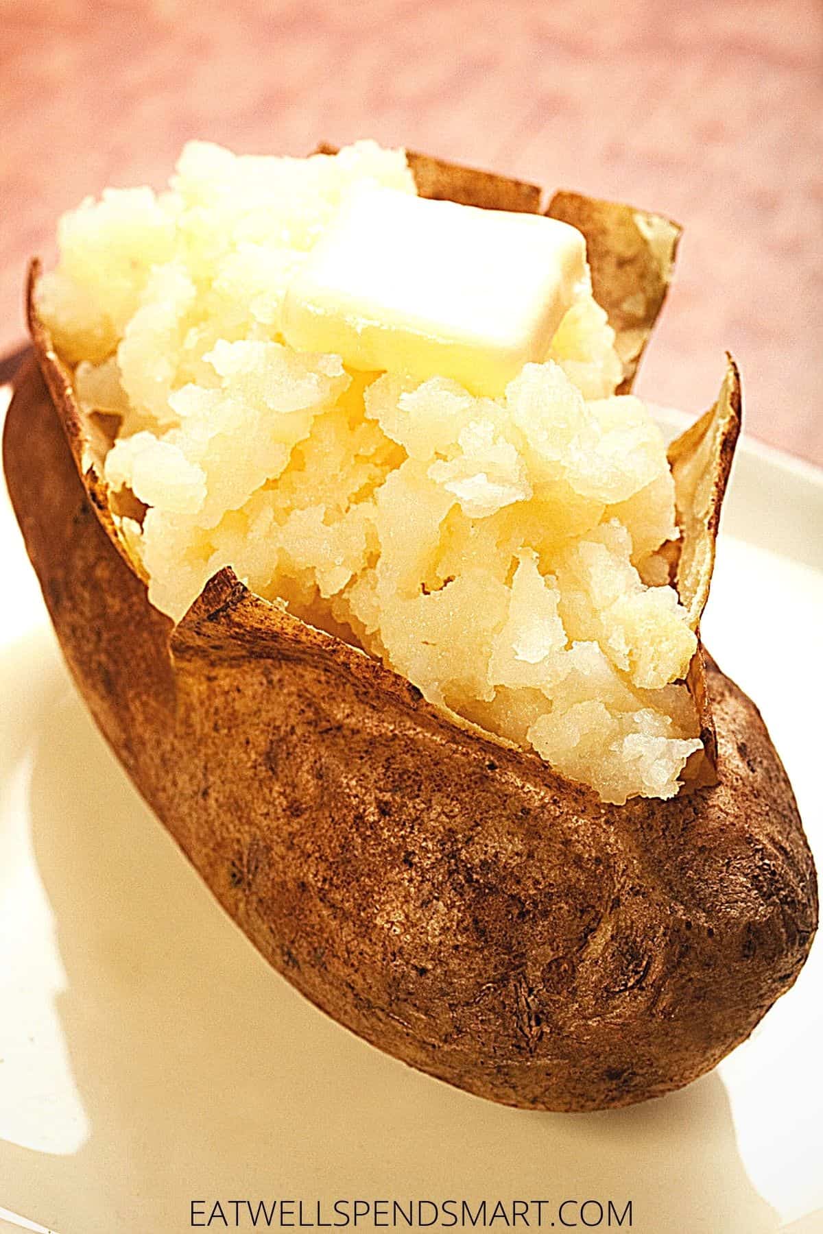baked potato topped with butter on a white plate