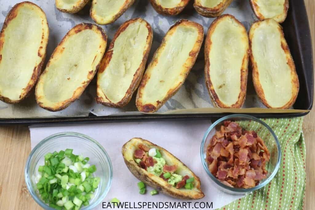 Potato skins on a tray with bacon and green onion topping