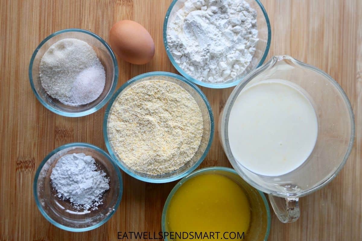 Egg, bowls of flour, cornmeal, butter, milk, salt, baking powder, and sugar