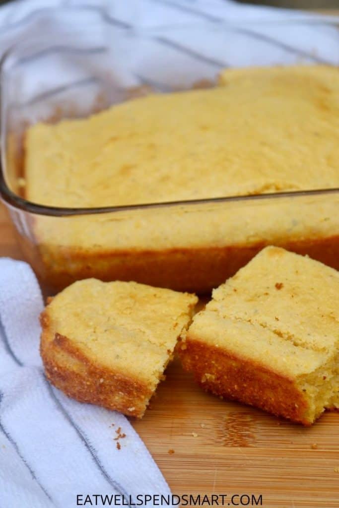 Two slices of homemade cornbread in front of a pan of cornbread