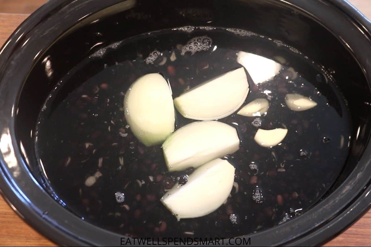 black beans, quartered onion, garlic cloves, and bay leaf in slow cooker