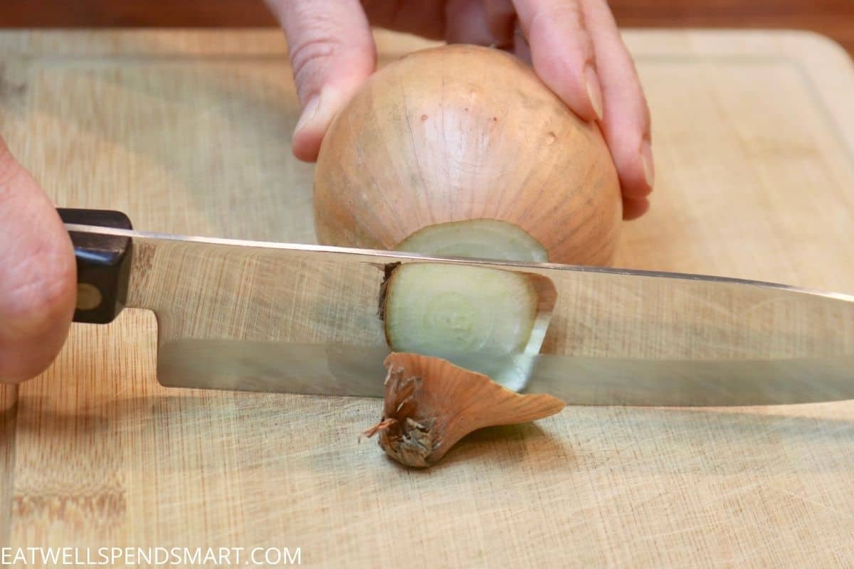 knife cutting the stem end off of an onion