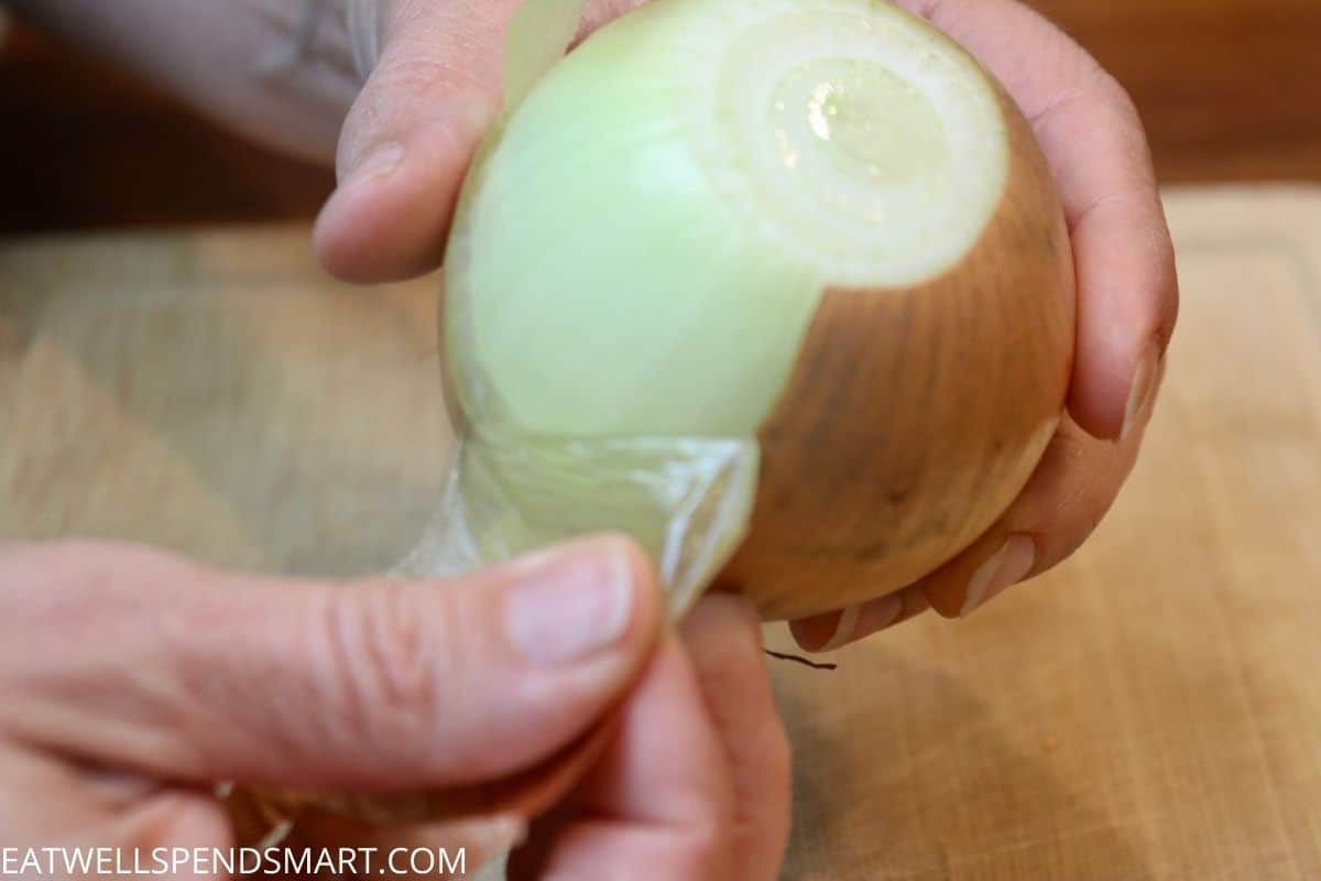 hand peeling the skin off an onion