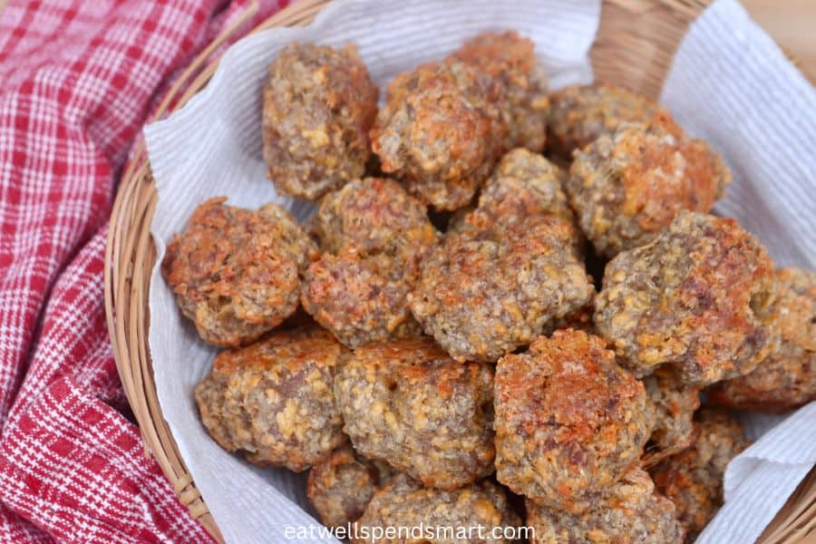 sausage balls in a paper towel lined basket surrounded by a red and white plaid towel