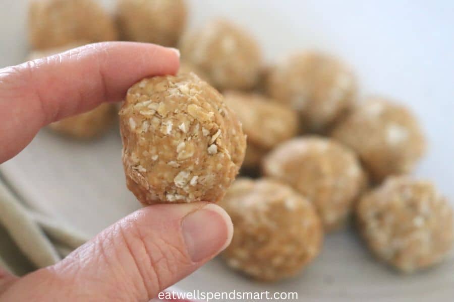 index finger and thumb holding a peanut butter oatmeal ball