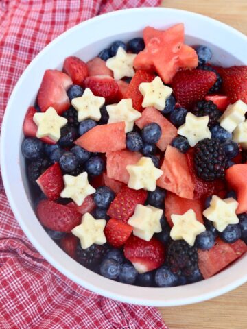 white bowl with watermelon, strawberries, blueberries, blackberries, and star shaped bananas