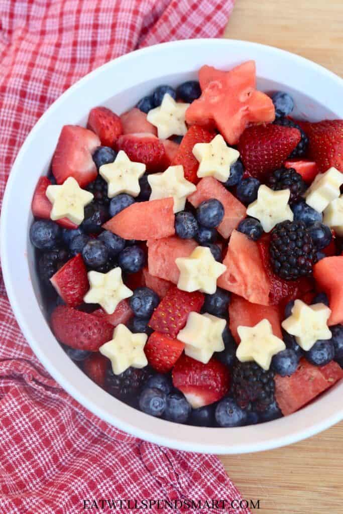 white bowl with watermelon, strawberries, blueberries, blackberries, and star shaped bananas